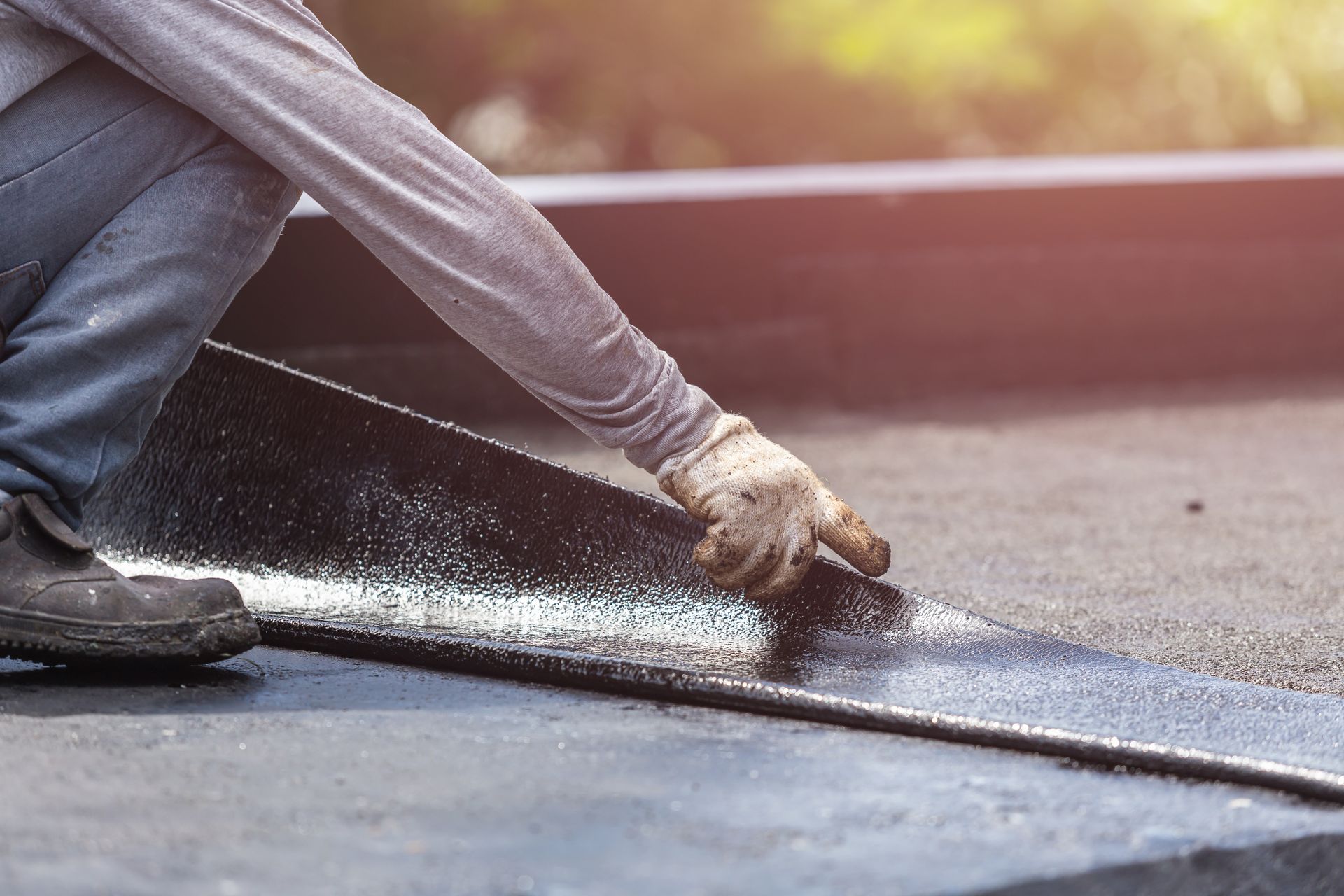 Group of workers installing tar foil on the rooftop of building.