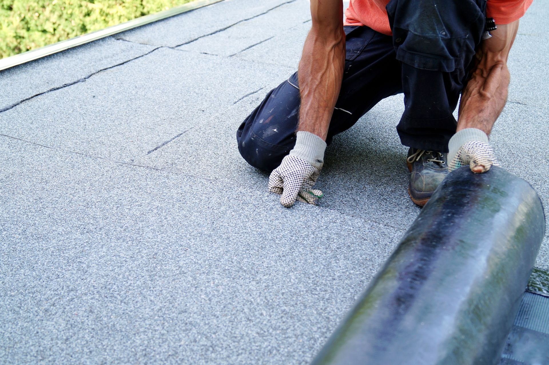 worker installing tar foil on the rooftop of building.