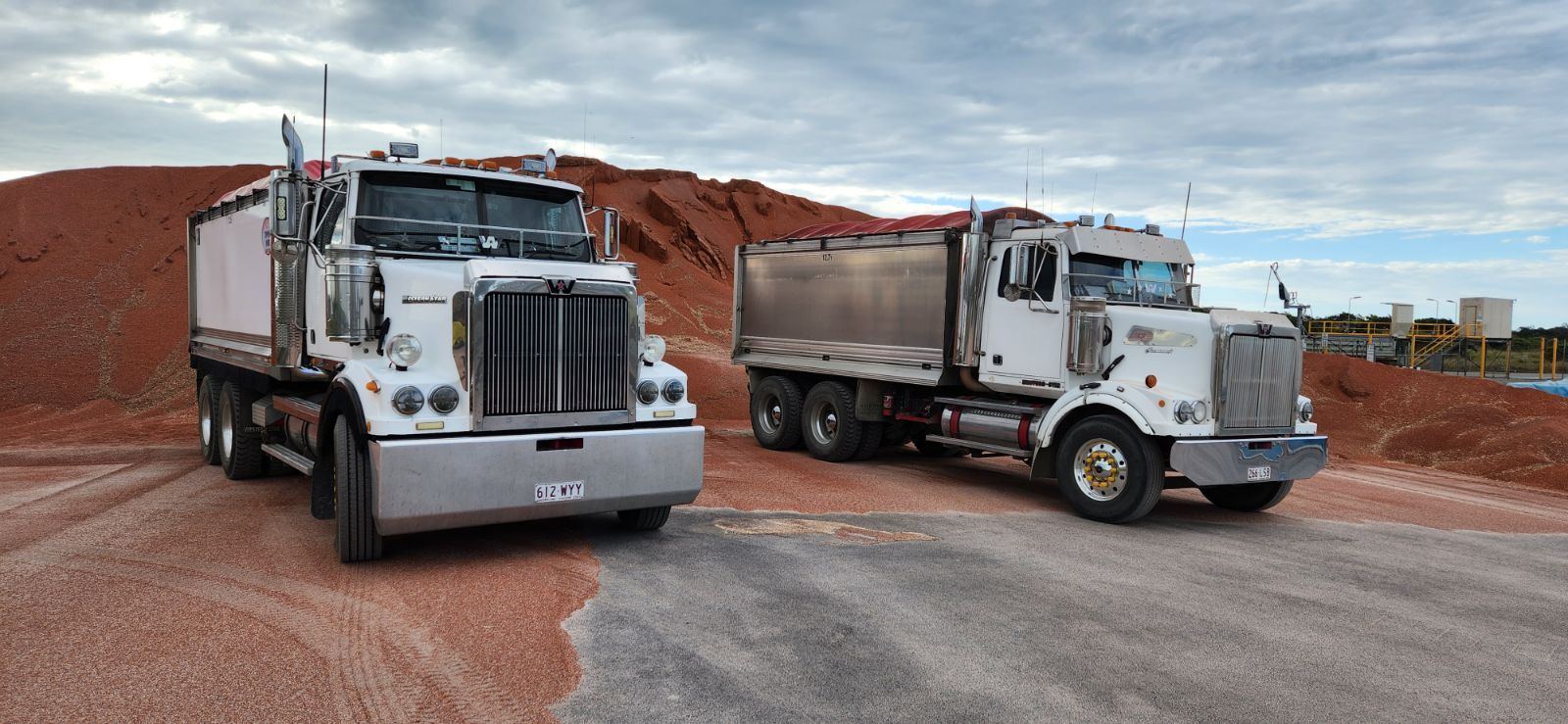 Two Semi Trucks Are Parked Next To Each Other On A Dirt Road — Petersen Tippers in Farleigh, QLD