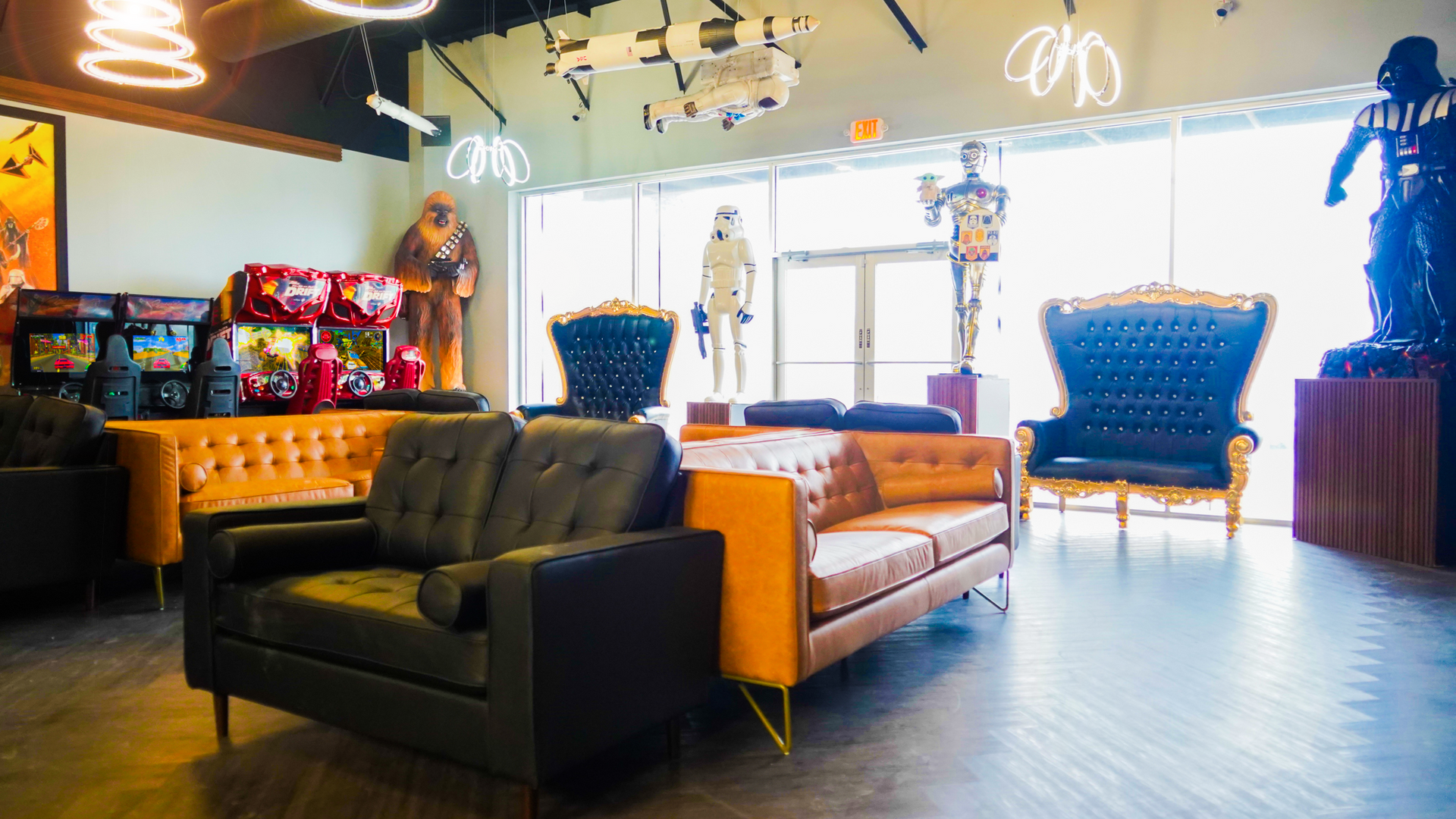 A lounge area featuring tufted black and orange sofas, ornate chairs, and Star Wars character statues.
