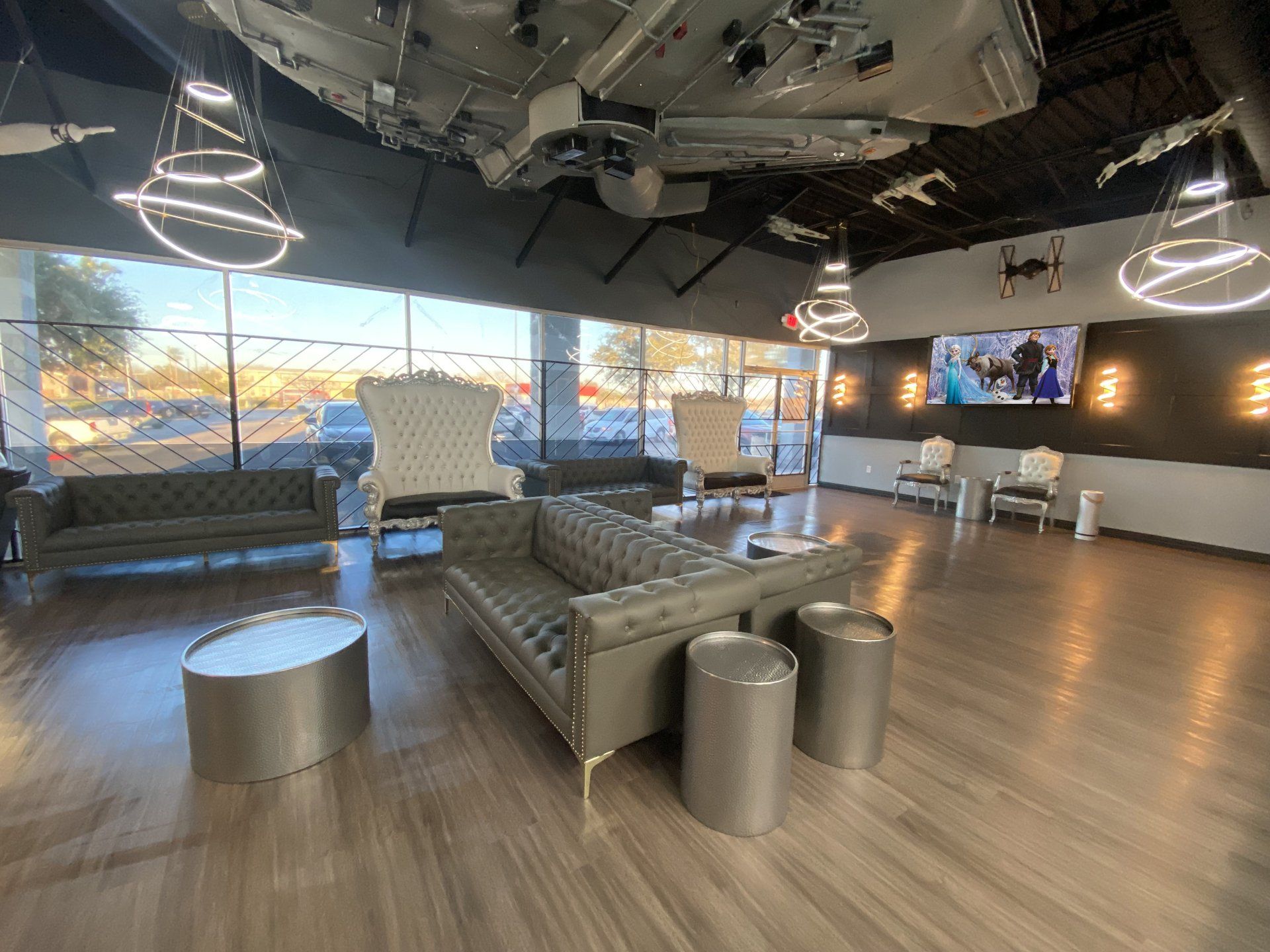 Modern lobby with gray leather couches, tufted white chairs, circular tables, and a Star Wars-themed ceiling installation.