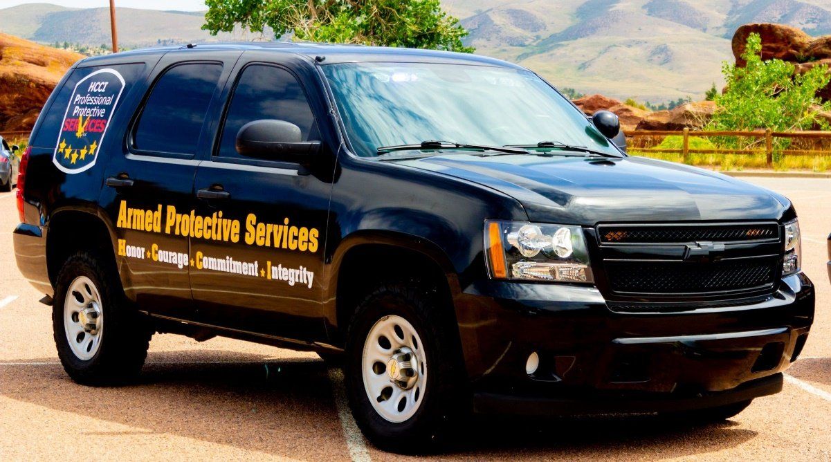 A black suv with armed protection services written on the side