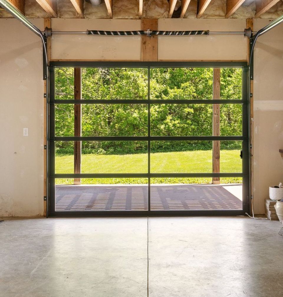Open glass garage door revealing a backyard.