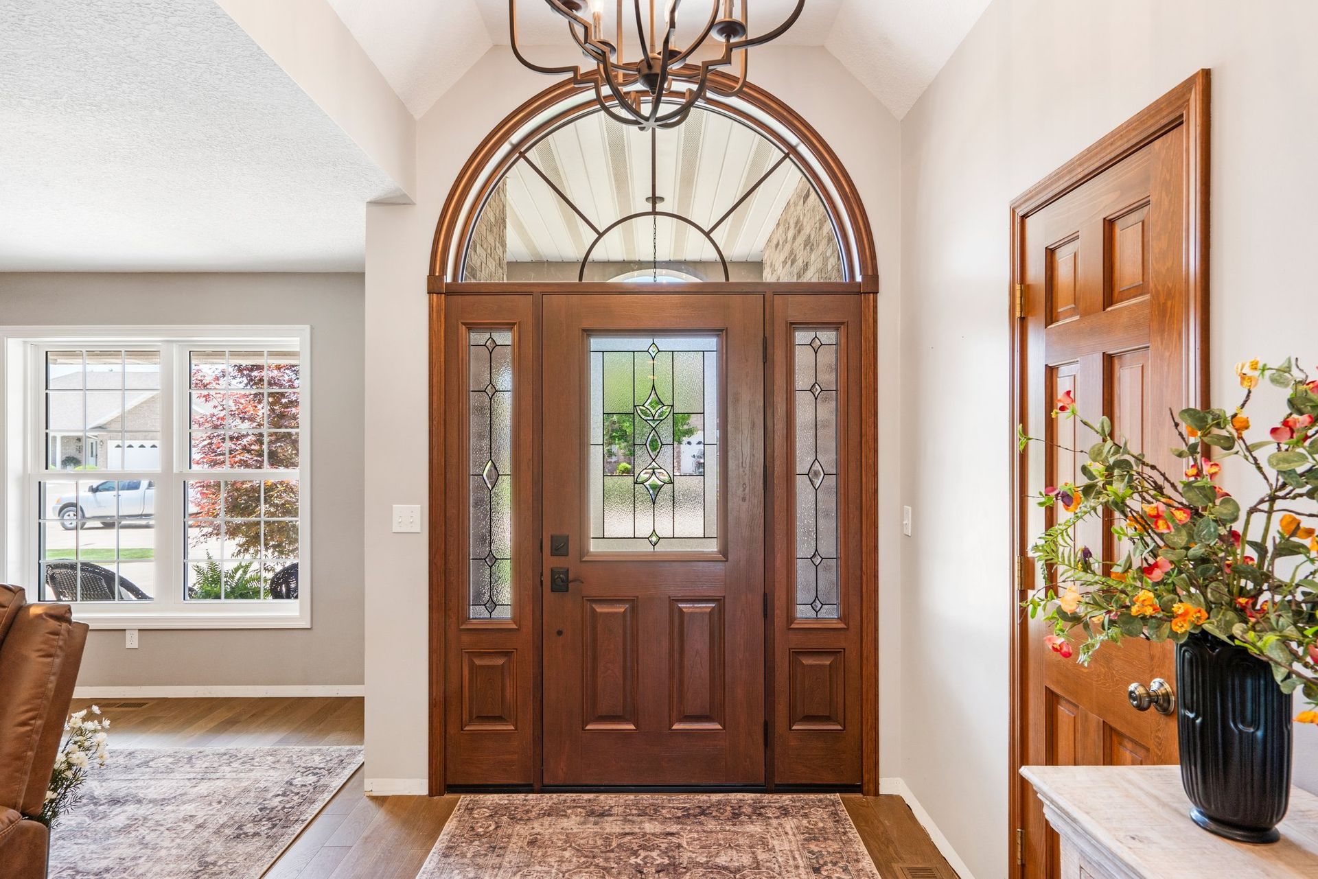 Wooden entryway with arched transom and sidelights, chandelier, interior.