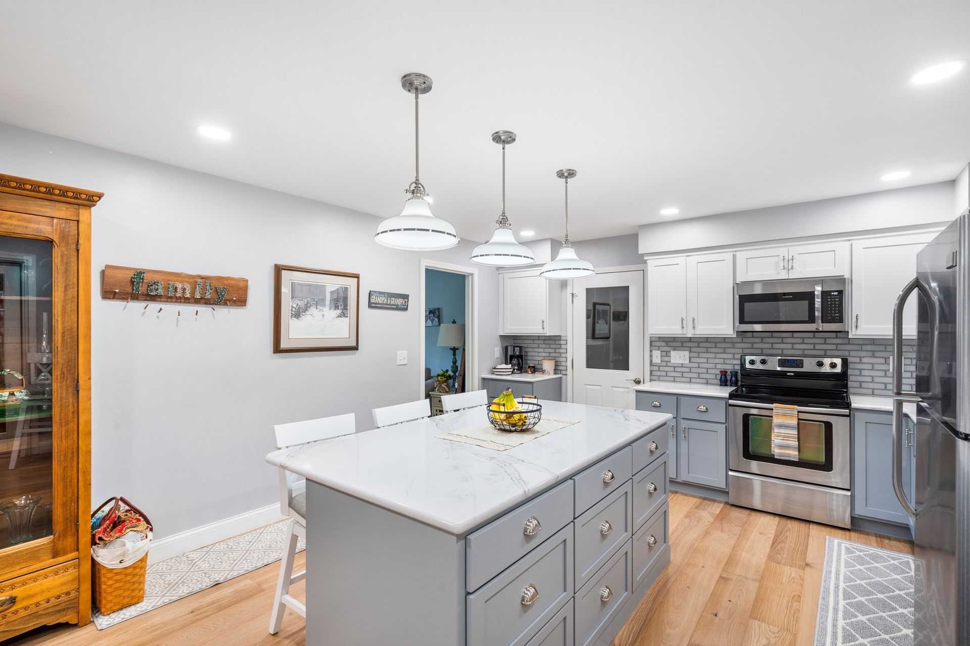 Kitchen with a gray island, white countertops, and stainless steel appliances.