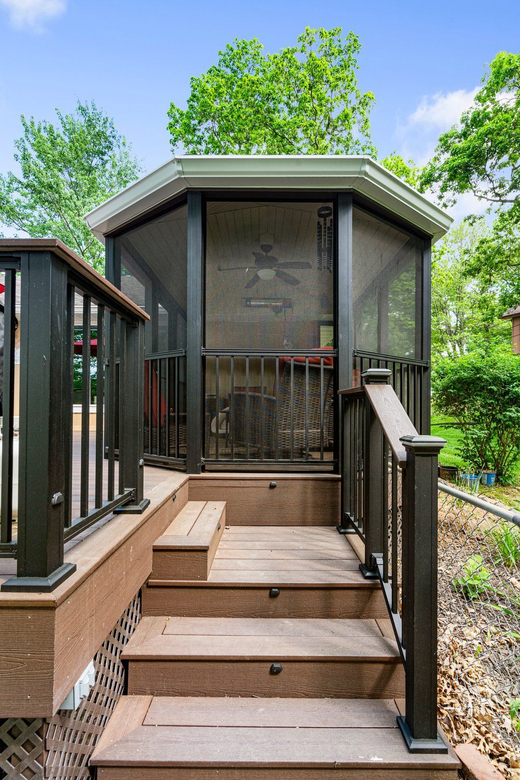 A modern screened in porch with green trees in the background. 