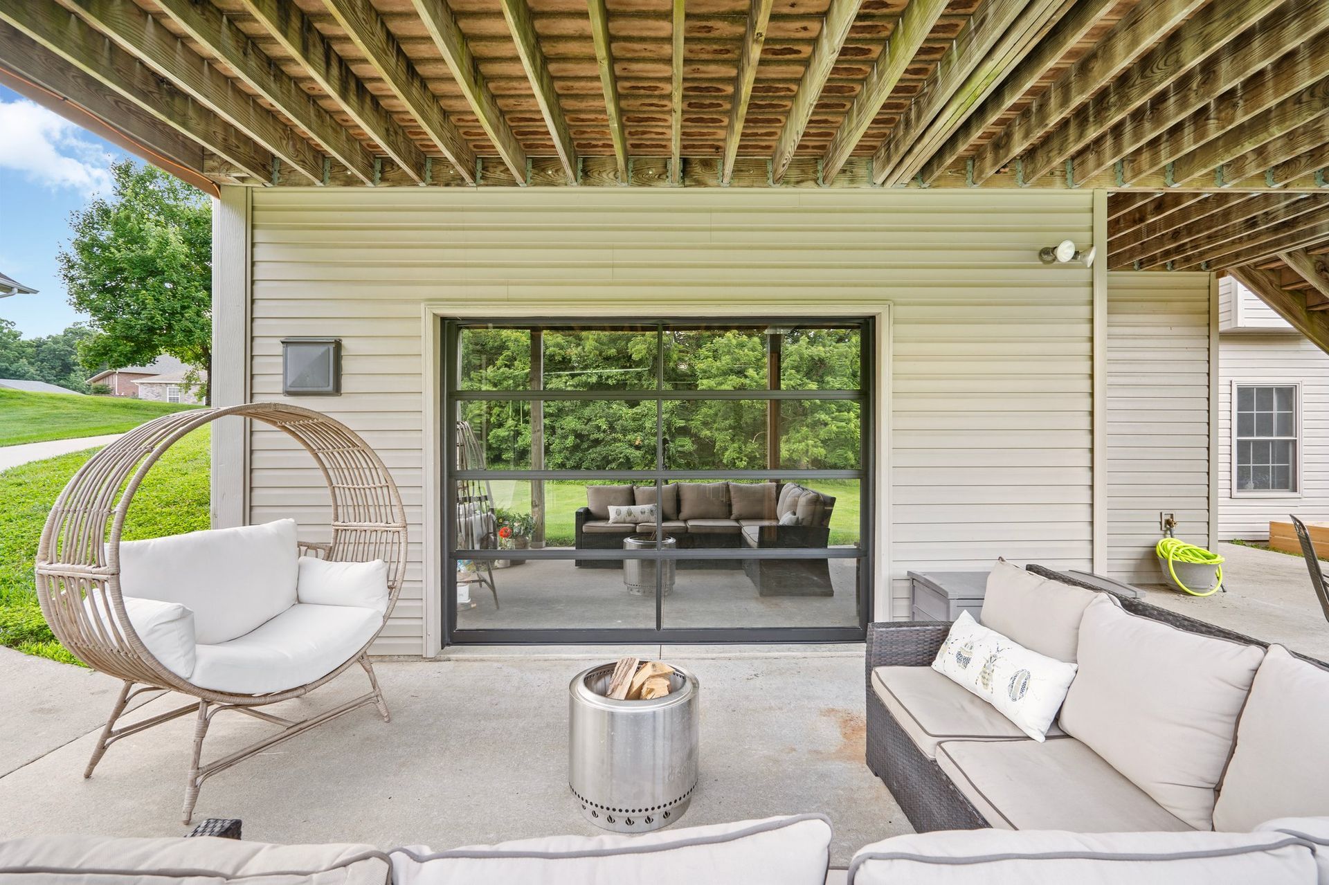 Outdoor patio with seating, fire pit, and a glass door opening to a living area.
