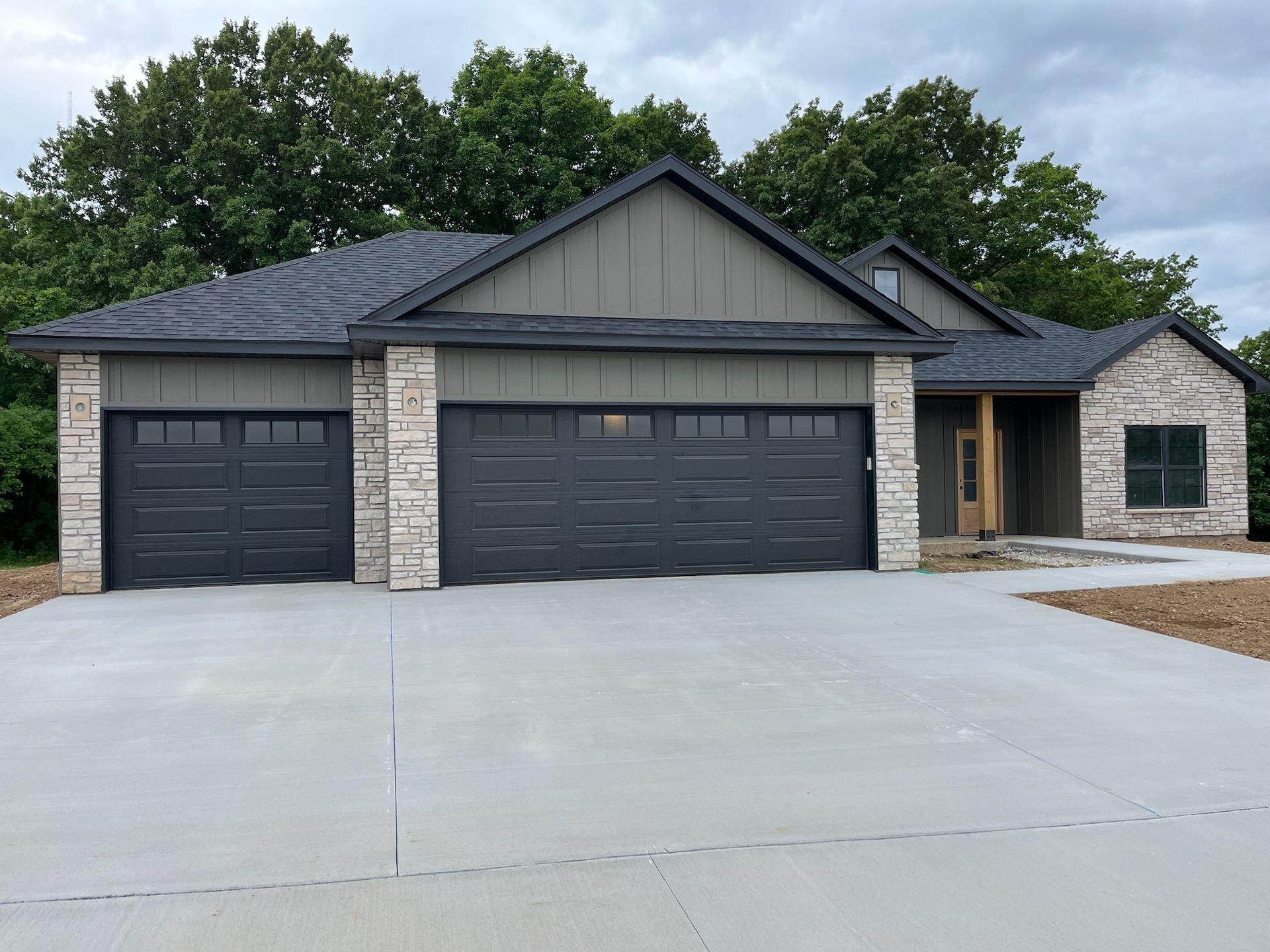 Gray and stone house with a two-car garage, set on a concrete driveway.