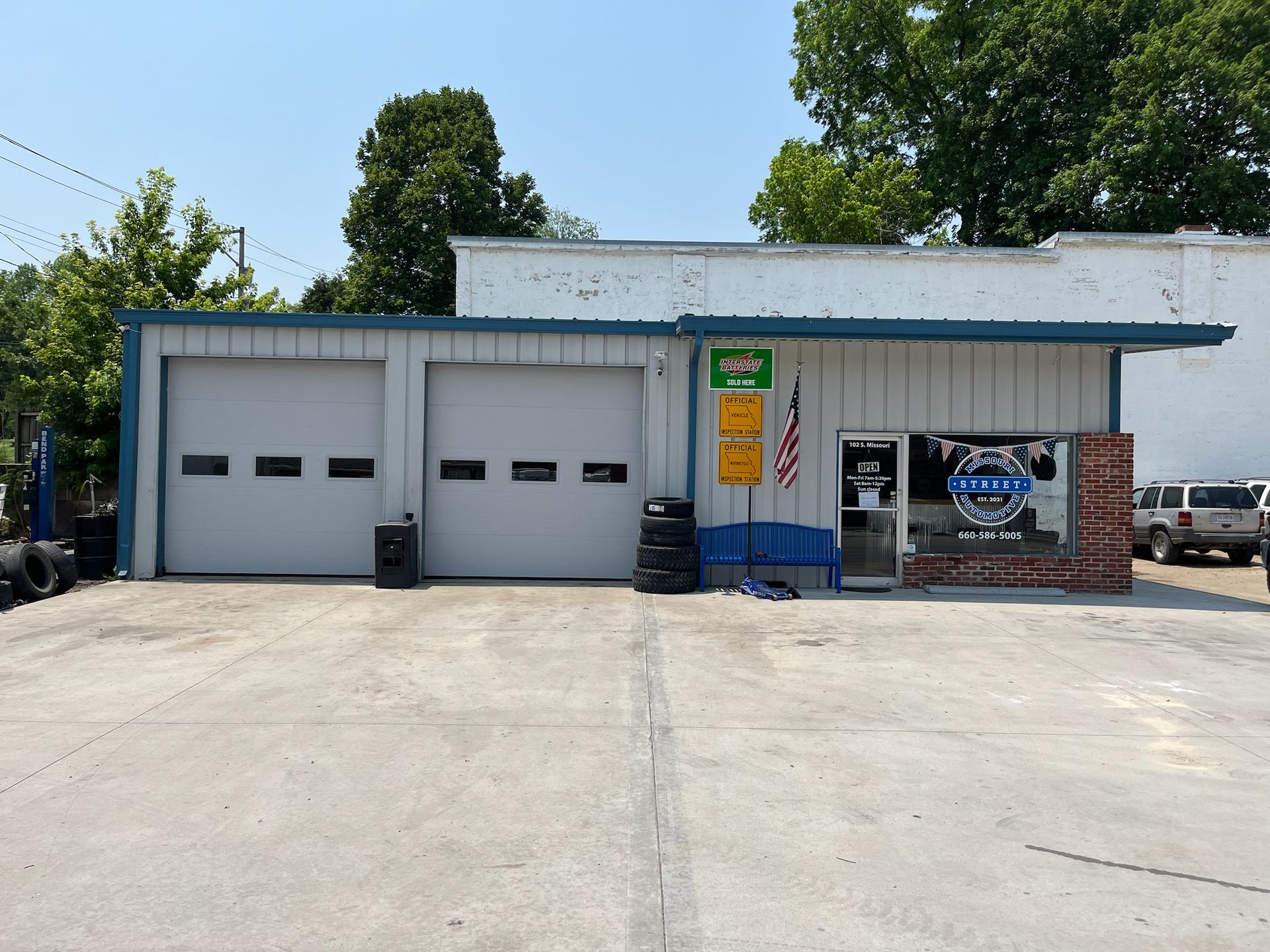 Auto repair shop with two garage doors and a small office under a blue awning.
