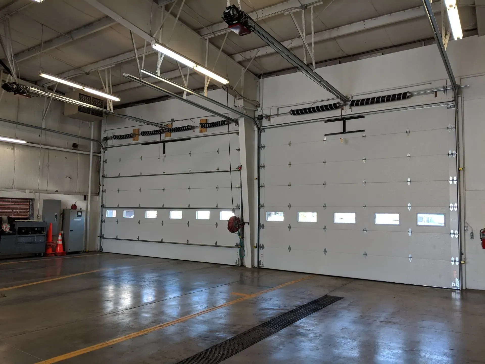 Two closed white garage doors inside a brightly lit service bay.