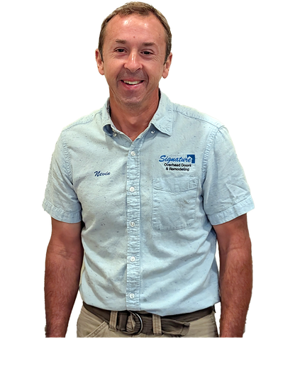 Man in light blue shirt, smiling, wearing a belt, in front of a white background.