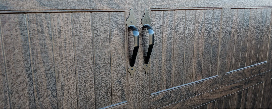 Two metallic bird statues mounted on a textured wooden surface.