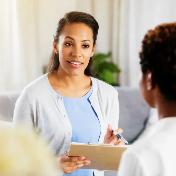 Doctor taking notes while speaking with a seated patient in a bright office