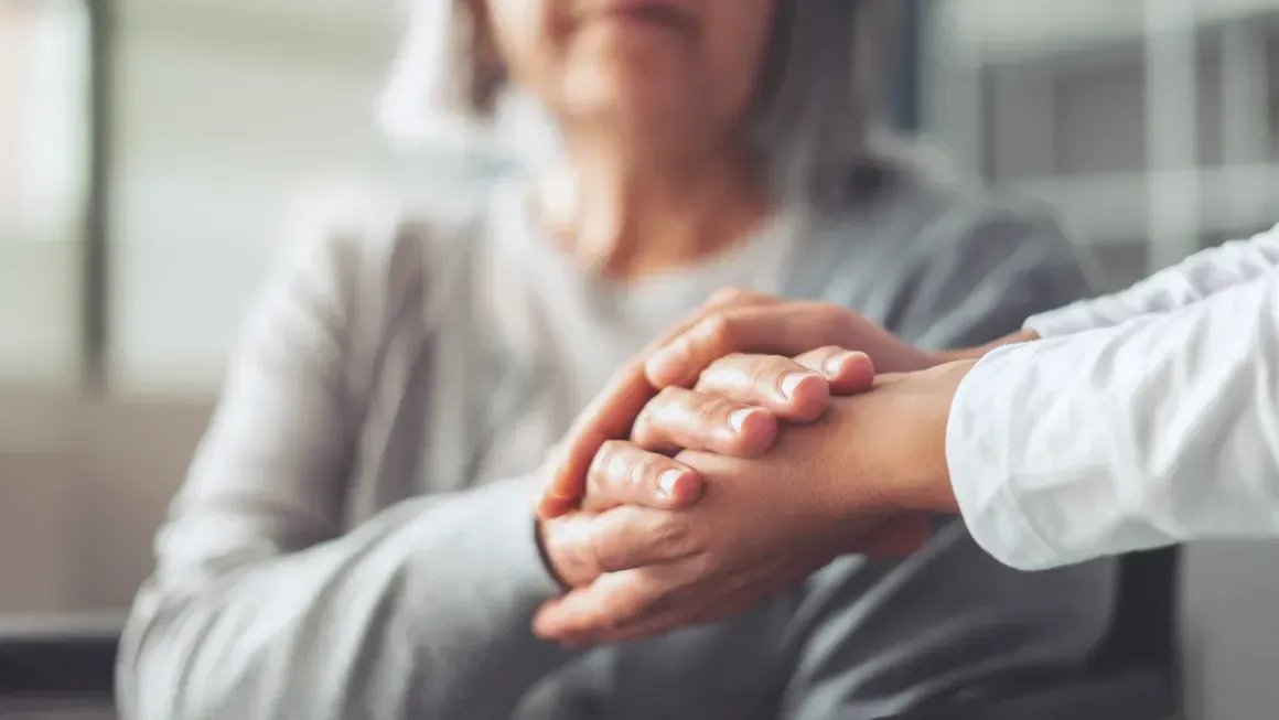 Hands clasped in a comforting gesture with a blurred person in the background