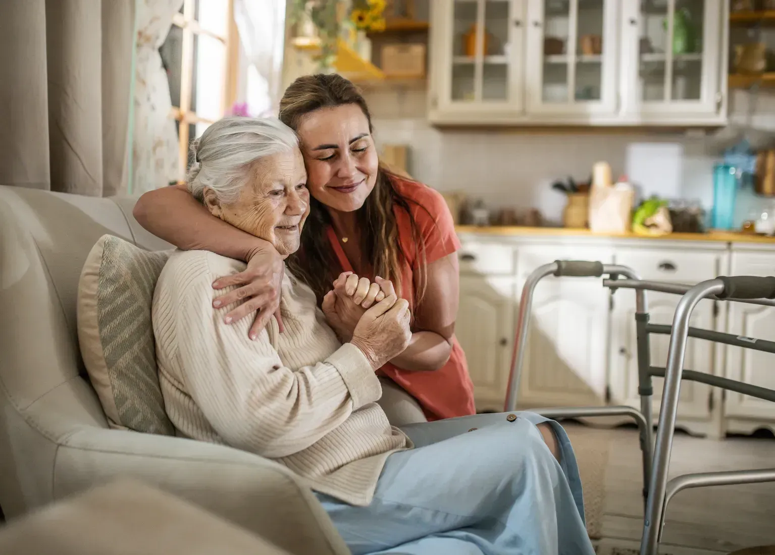 Two people embracing on a couch in a cozy living room, with a walker nearby