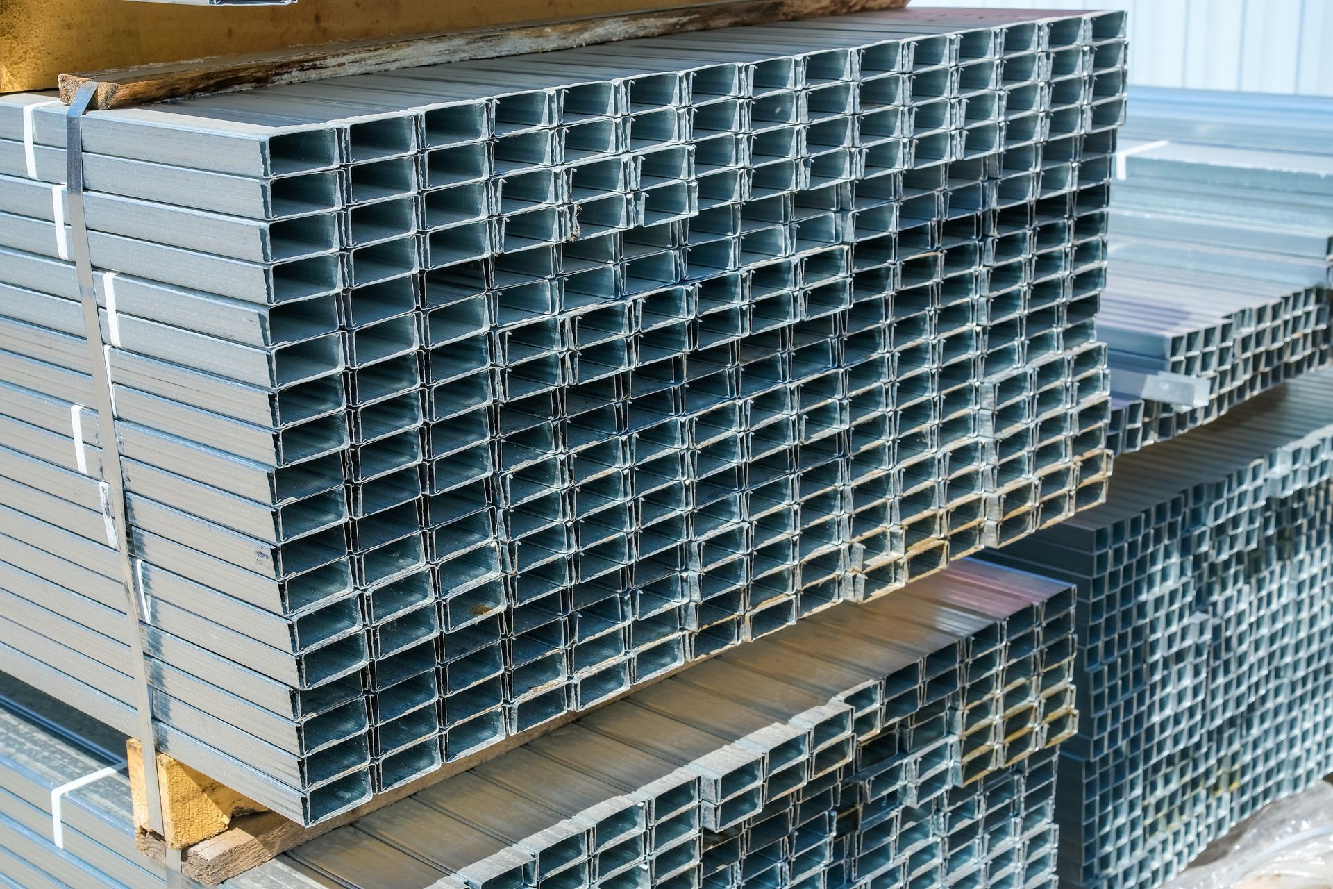 Bundles of galvanised steel stacked in a warehouse.