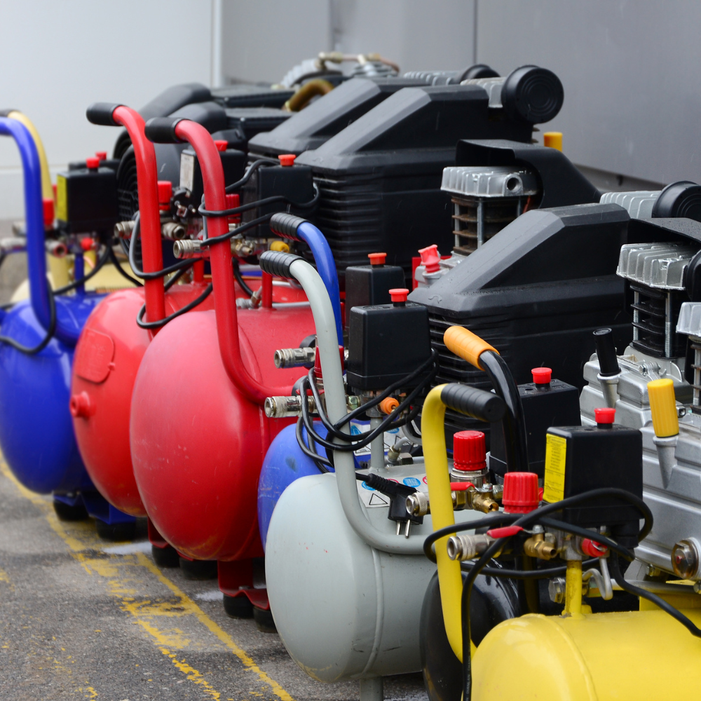 Row of colorful industrial backpack blowers lined up on a concrete floor