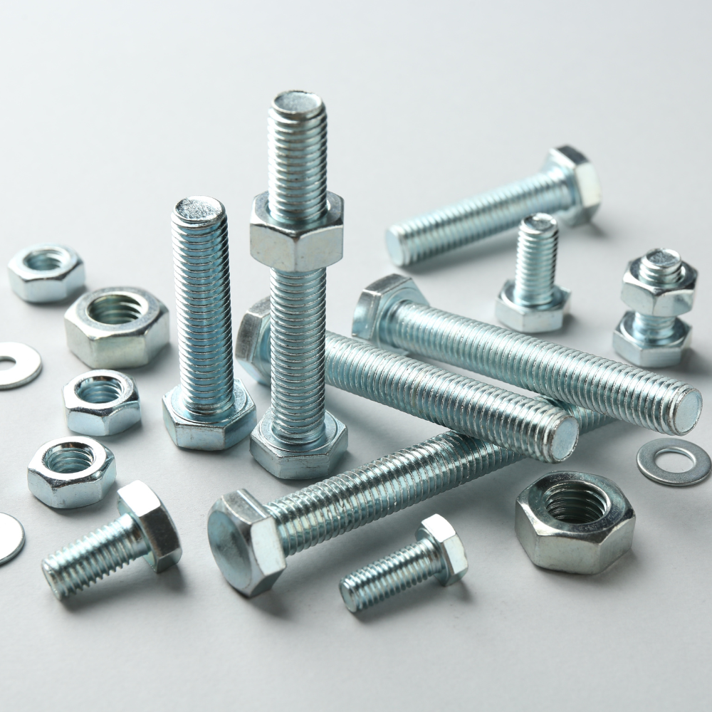 Assorted silver bolts, screws, nuts, and washers scattered on a white surface.