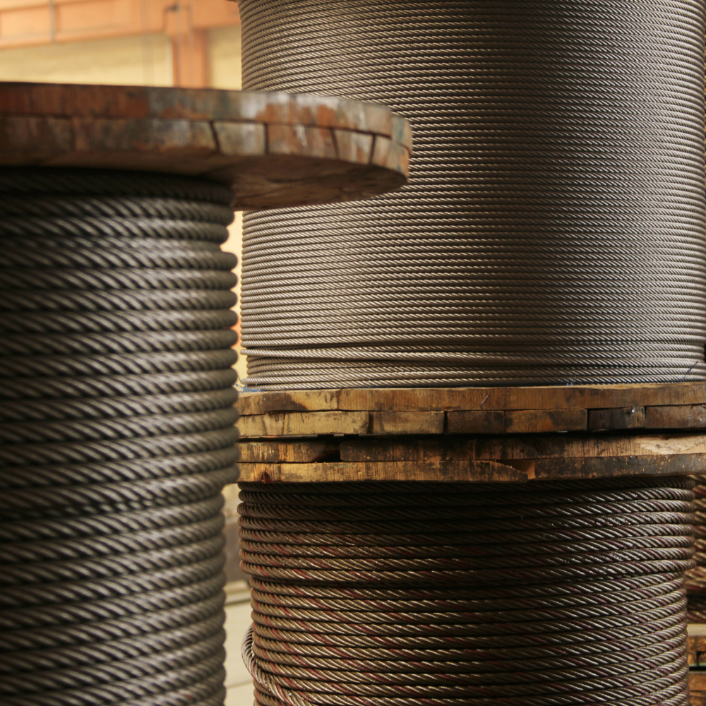 Close-up of stacked metal cable spools with coiled steel wire and wooden rims