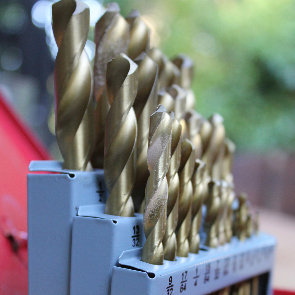 Assorted gold drill bits in a gray holder, arranged in a row outdoors