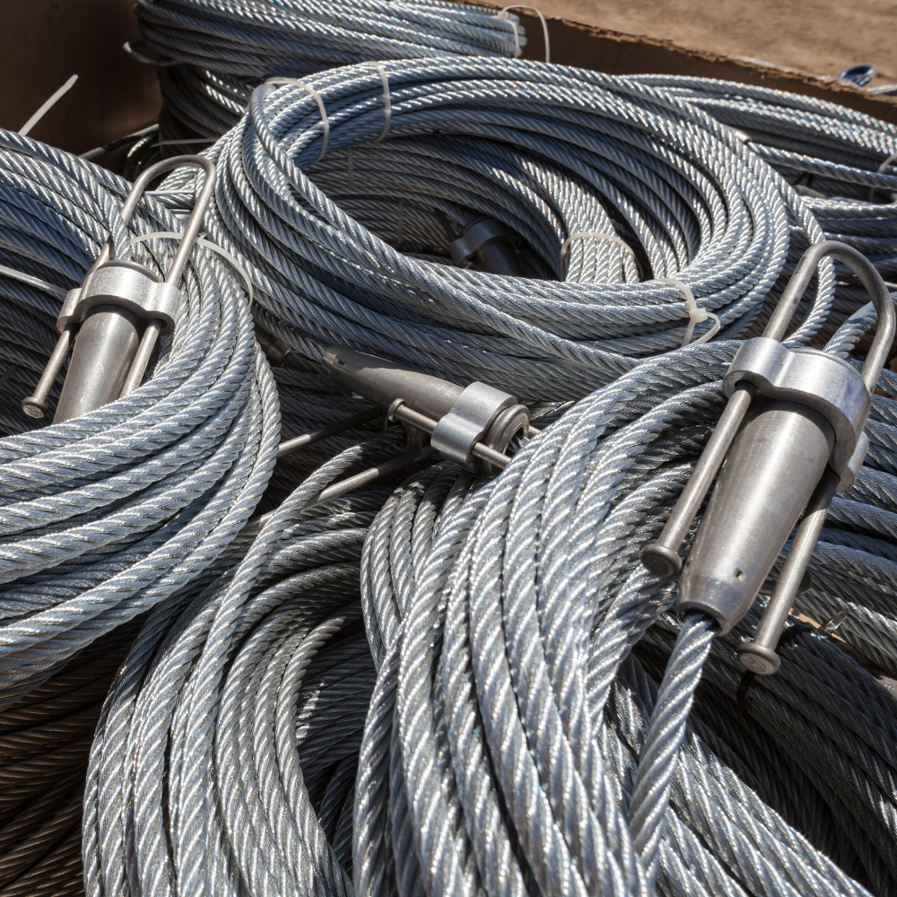Coiled steel wire ropes with metal fittings piled together in a close-up view