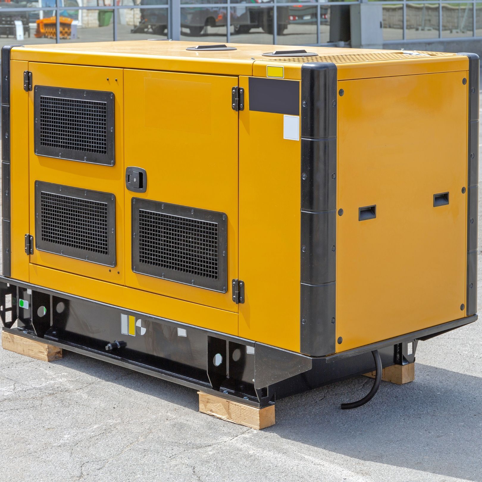 Yellow industrial generator on a pallet outdoors, with vents and a black base.
