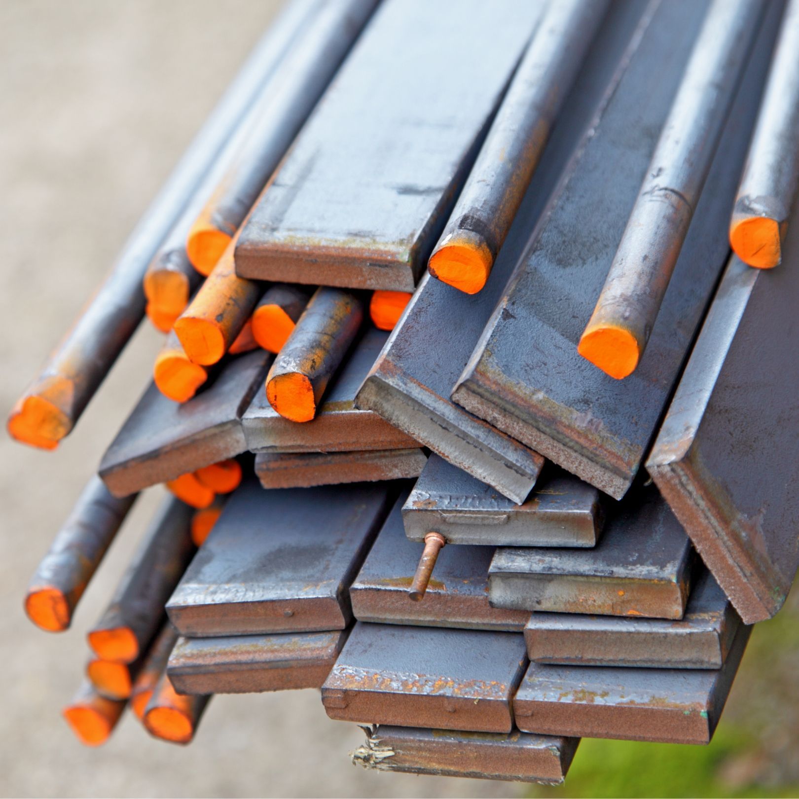 Stacked steel bars with bright orange ends on a white background