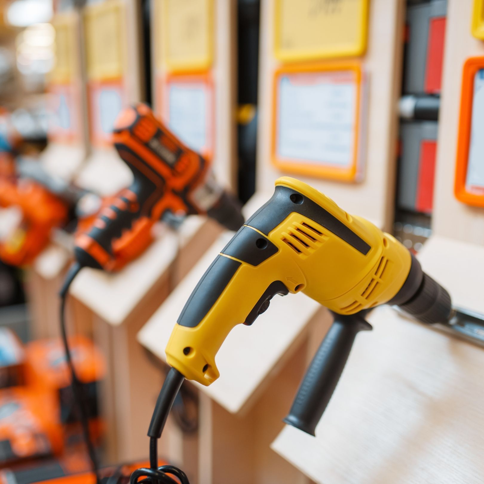 Yellow power drill displayed on a retail wall with other orange tools in the background