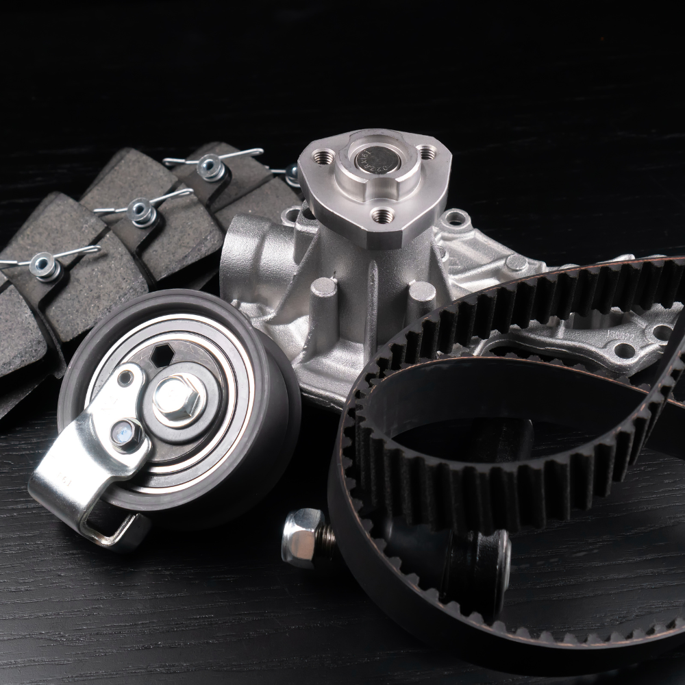 Automotive engine parts, including a timing belt, pulley, and metal components on a black background