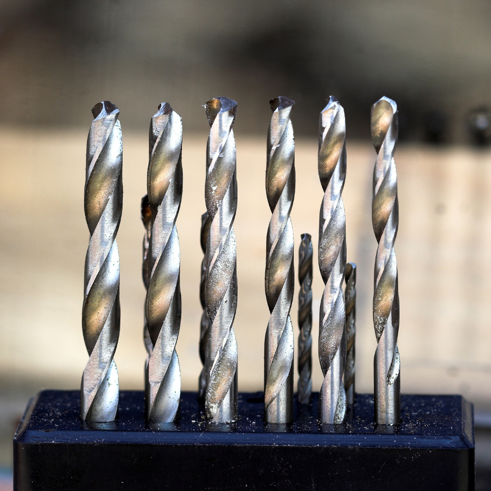 Small drill bits standing upright in a holder, shown close up against a blurred background