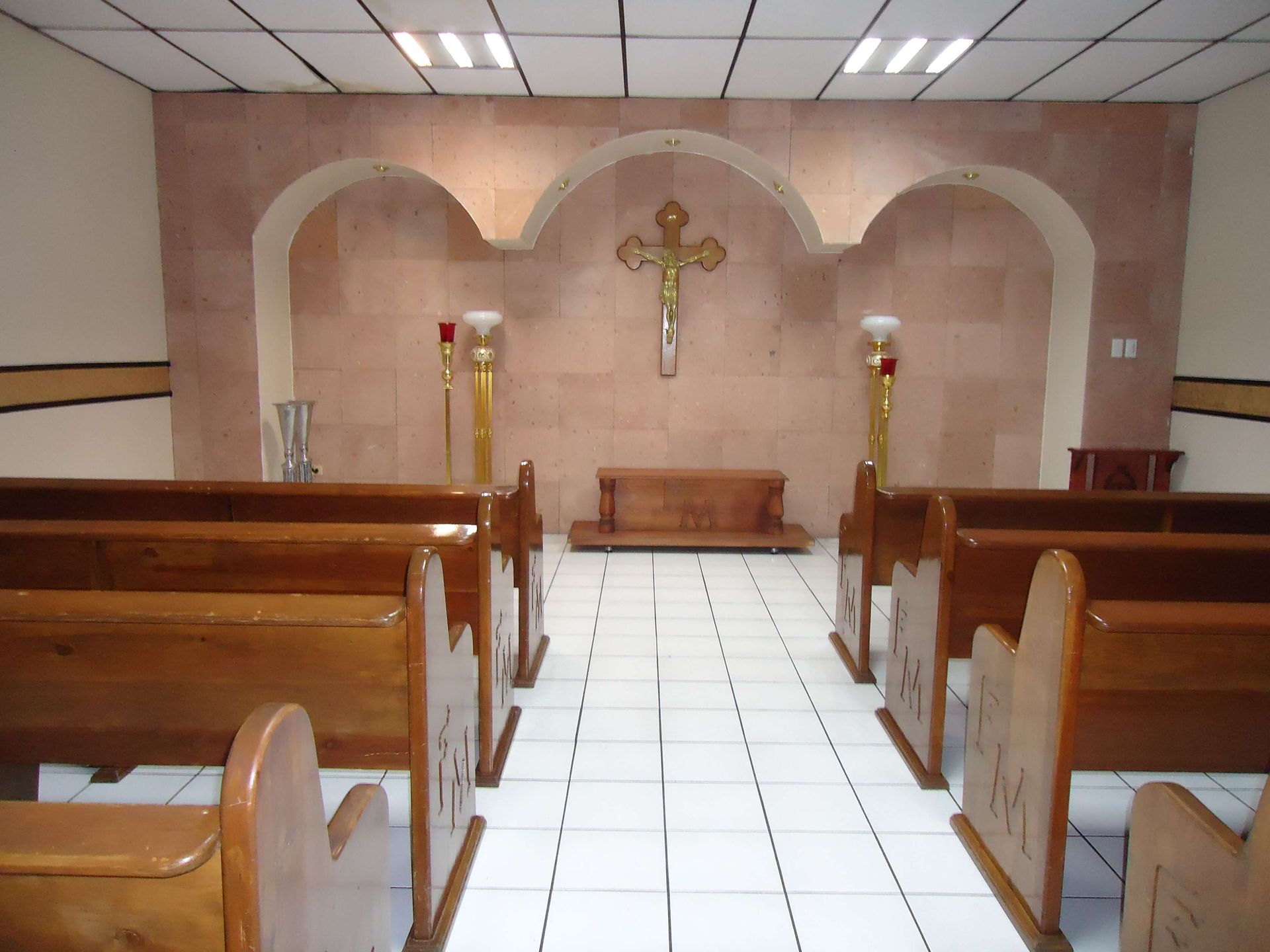 Una iglesia con bancos de madera y una cruz en la pared