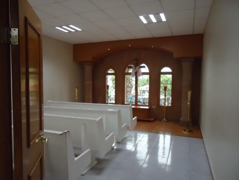 Una fila de bancos blancos en una habitación con ventanas arqueadas.
