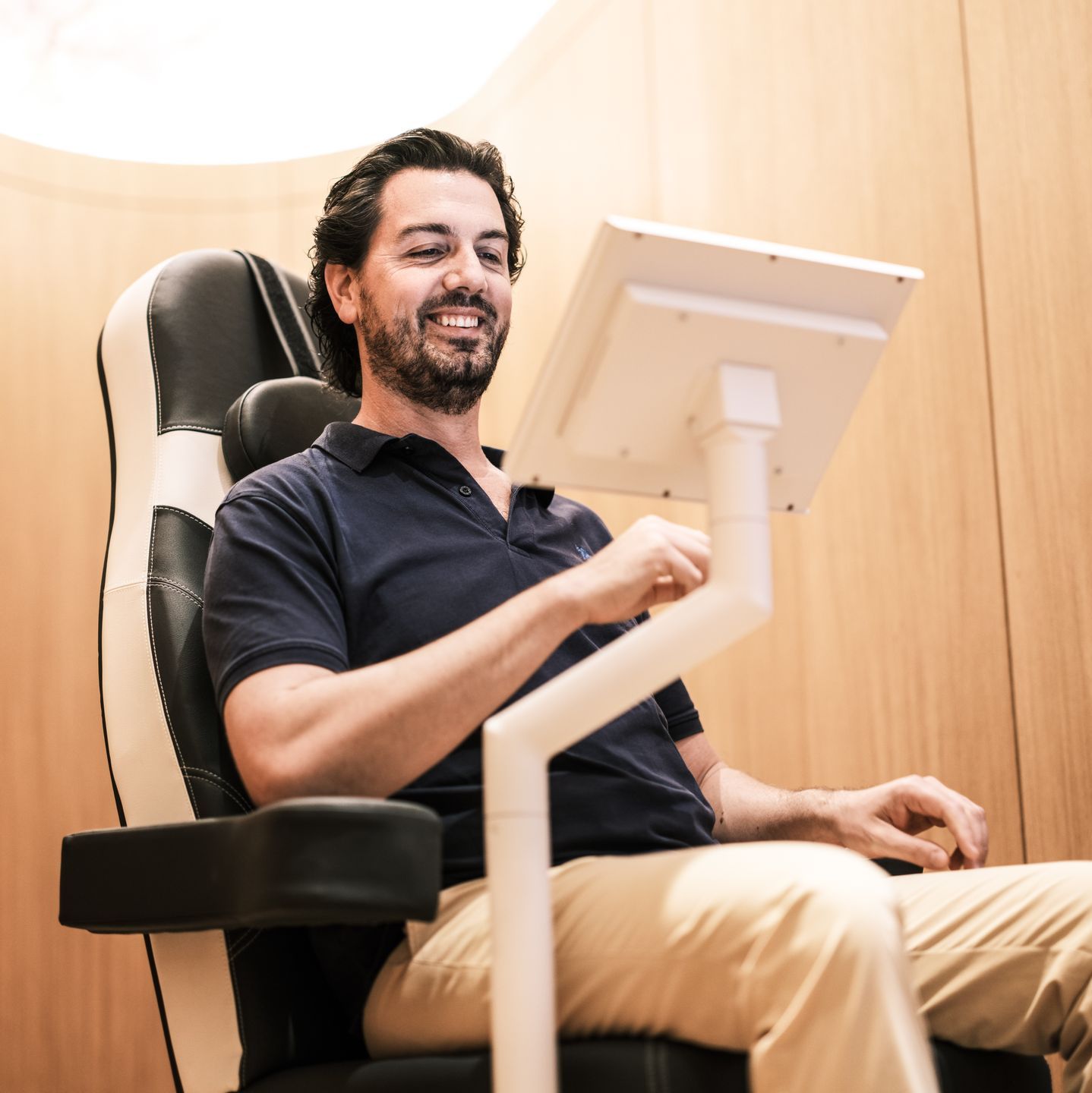 Ein Mann sitzt auf einem Stuhl und benutzt einen Computermonitor.