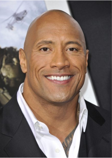 Dwayne (The Rock) Johnson A bald man in a suit and white shirt smiles for the camera