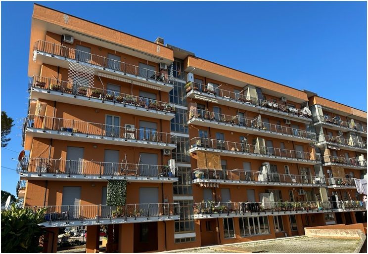 Condominio con facciata arancione e balconi sotto un cielo azzurro e terso.