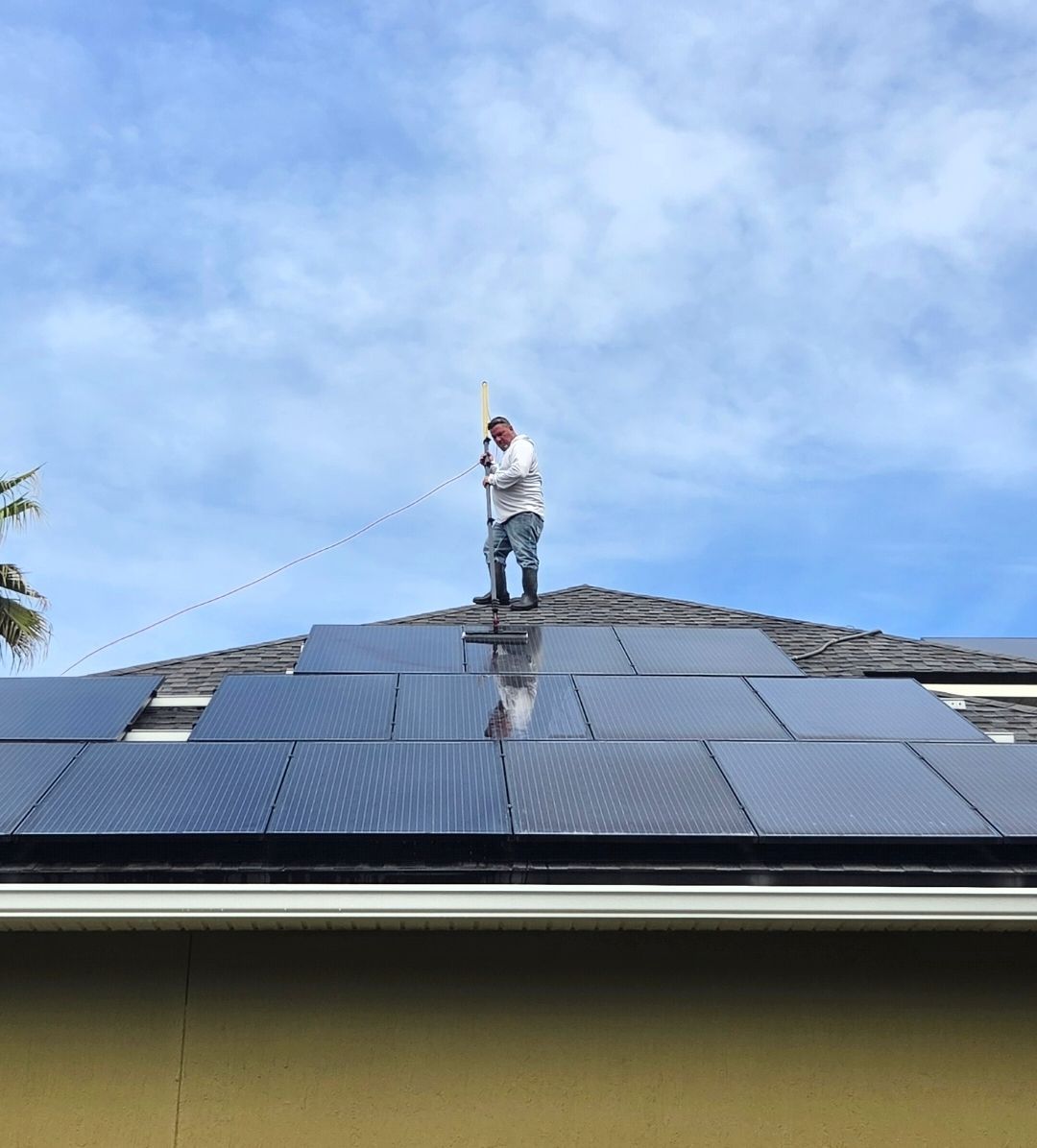 Worker on a rooftop installing solar panels under a blue sky
