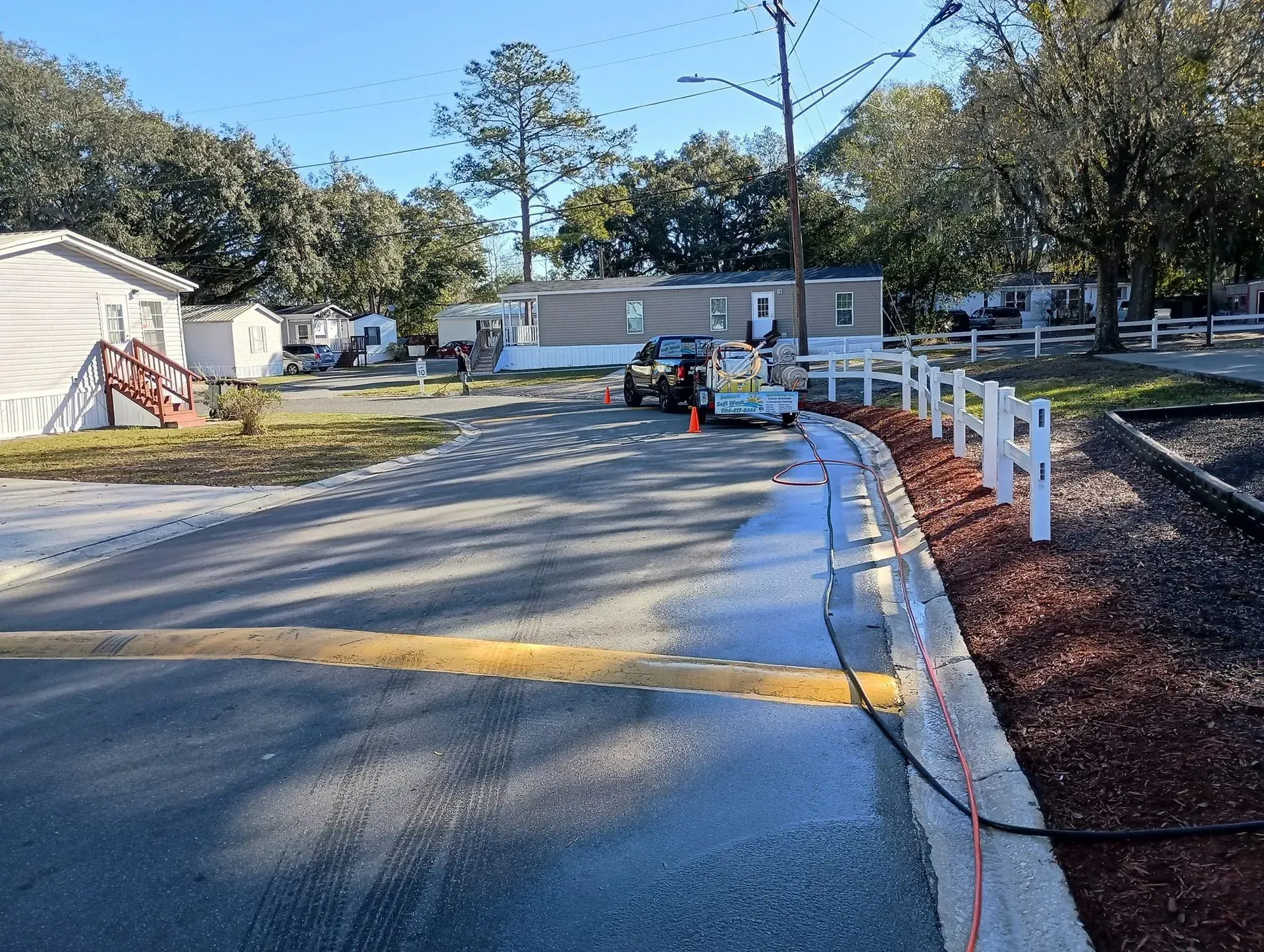 Roadwork on a curved road with cones, barriers, and white posts beside a trench under construction.