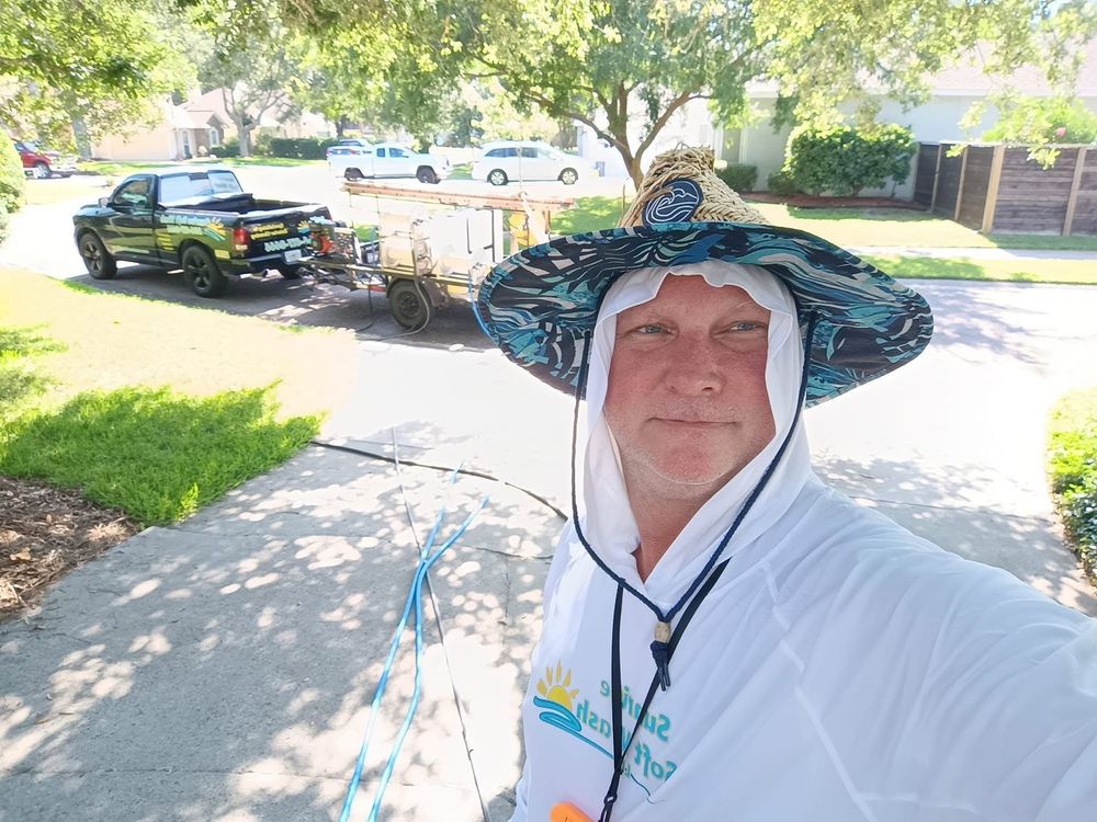 Smiling person in black hoodie and hat taking a selfie beside a utility vehicle at a house outdoors