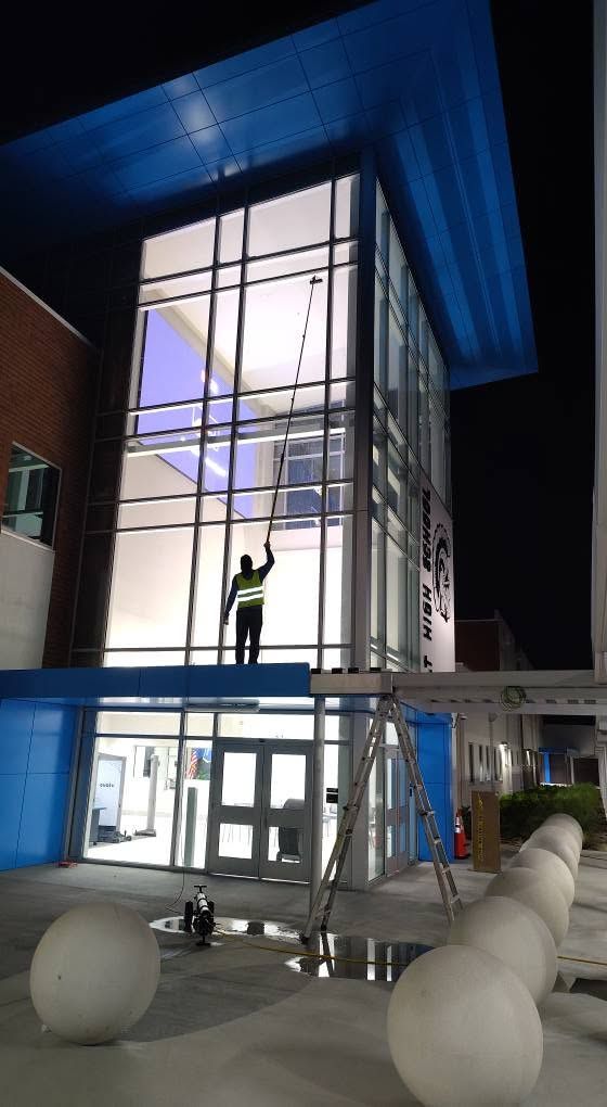 Two window cleaners on ropes cleaning glass windows of a modern office building.