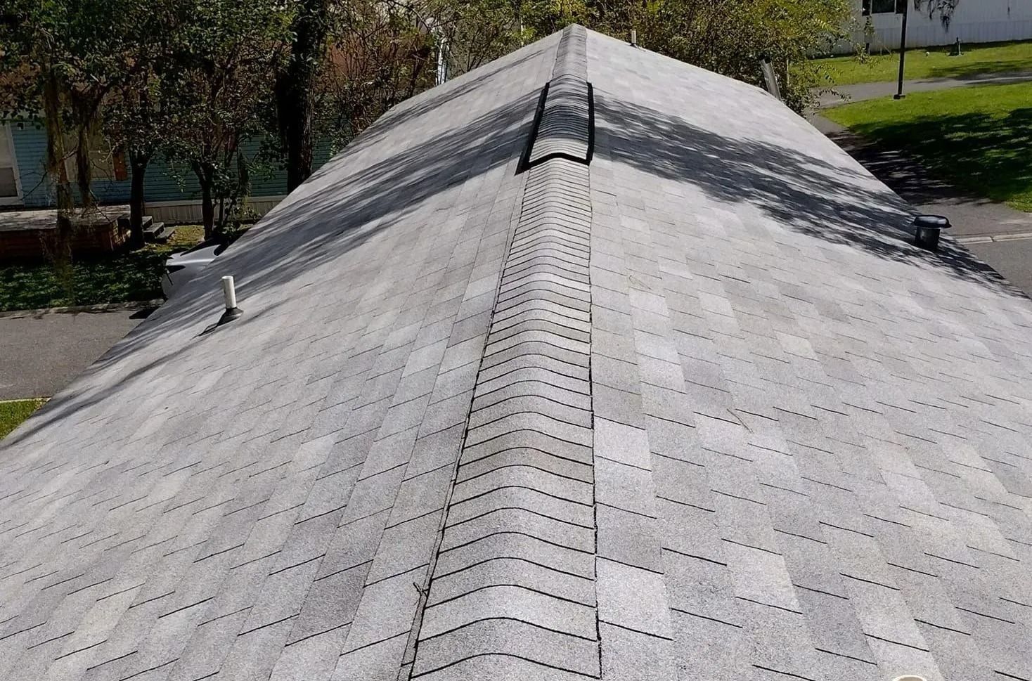 Shingled roof ridge with skylight, viewed from above on a sunny day