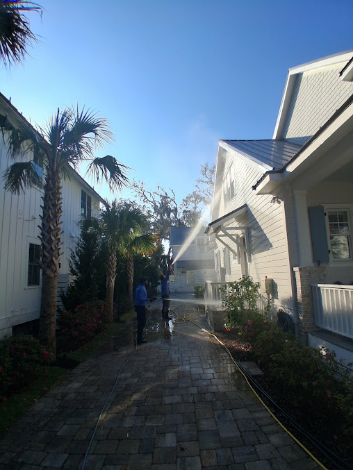 Sunlit walkway between white houses with palm trees and a person walking ahead