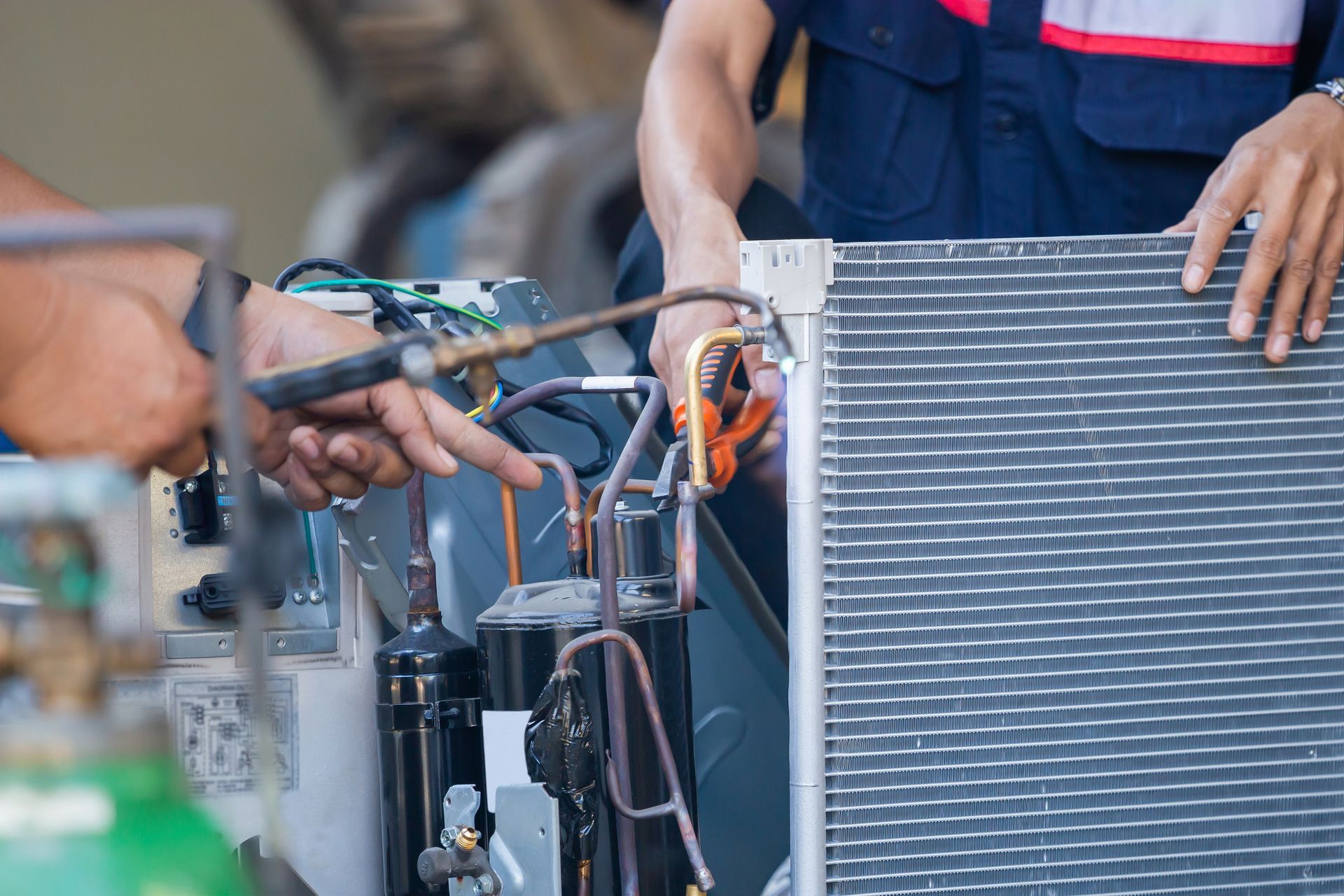 Technicians performing HVAC heating and cooling system repair with oxyfuel welding tools on site