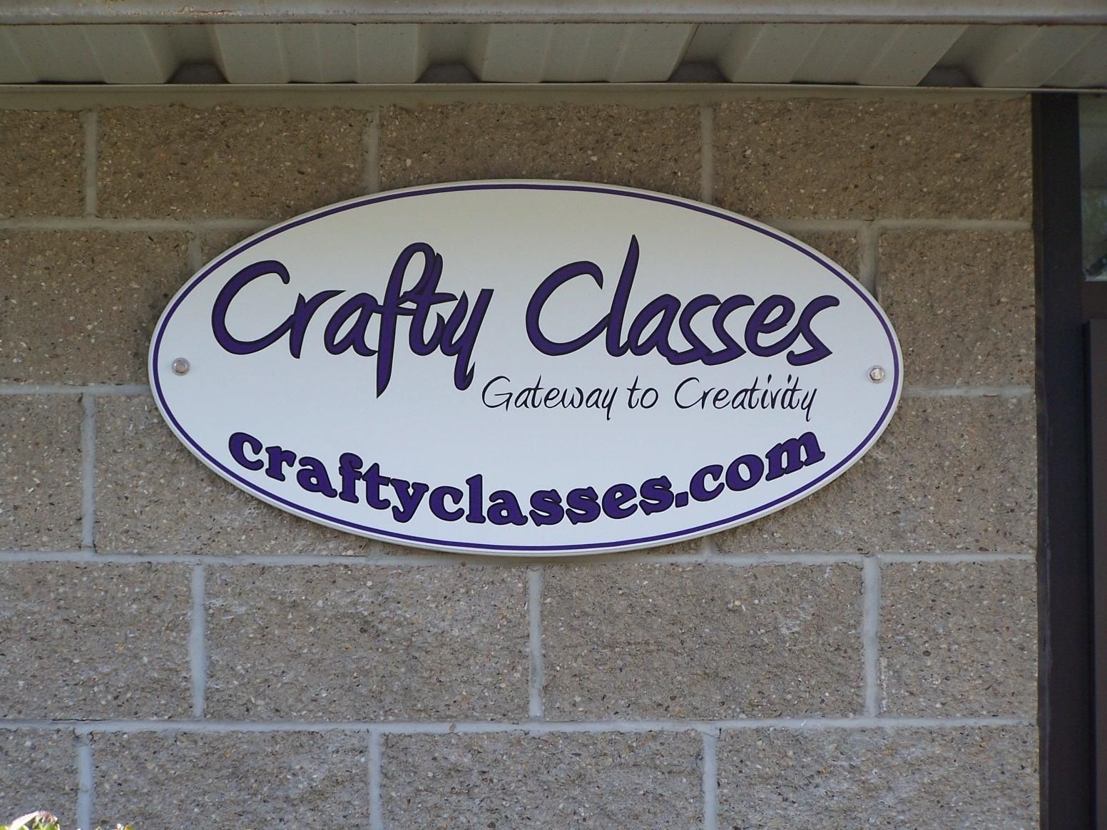 A sign for crafty classes hangs on a brick wall