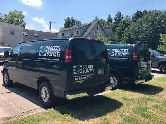 Two black vans are parked next to each other on the side of the road.