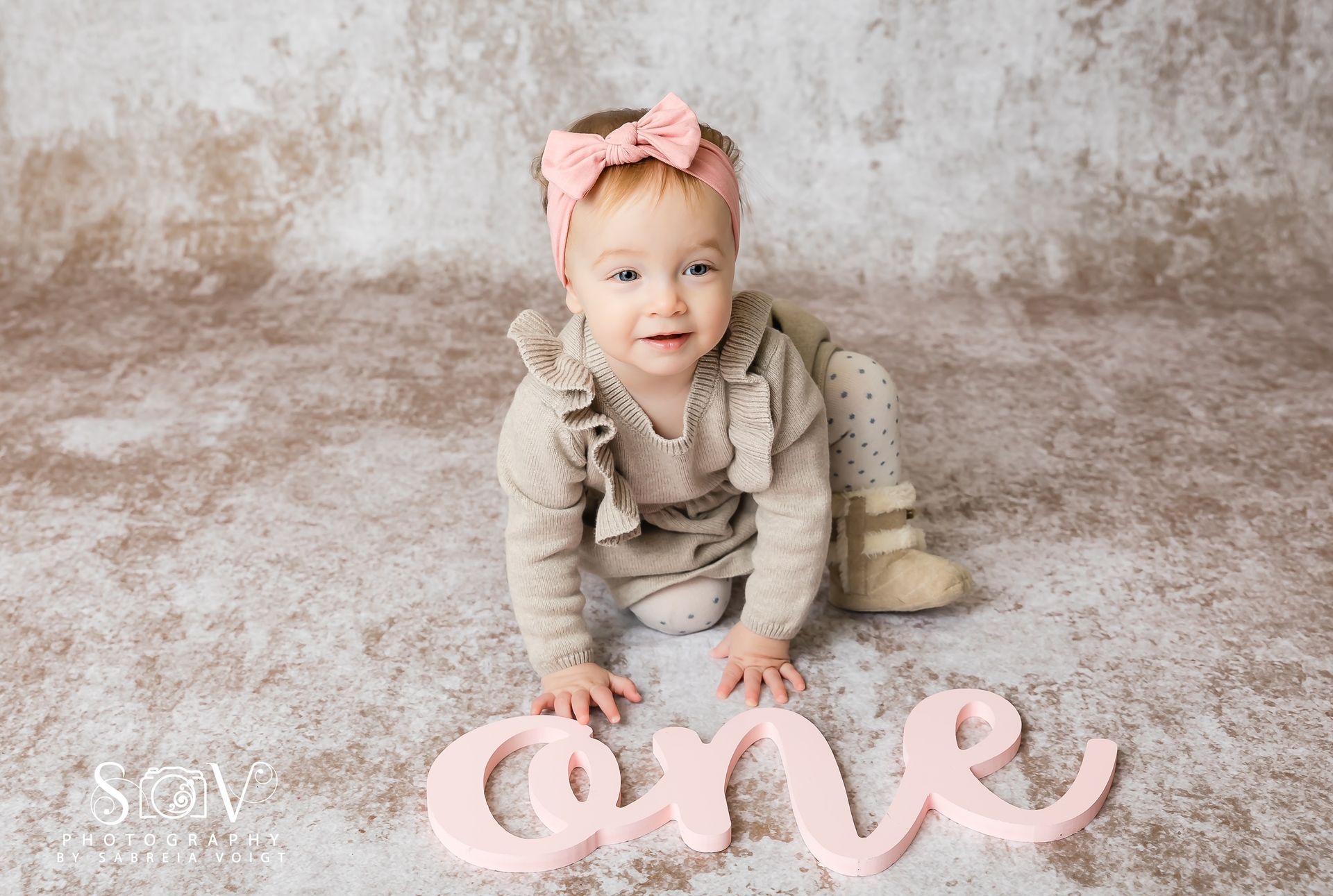 Baby crawling towards the camera, wearing a bow and 