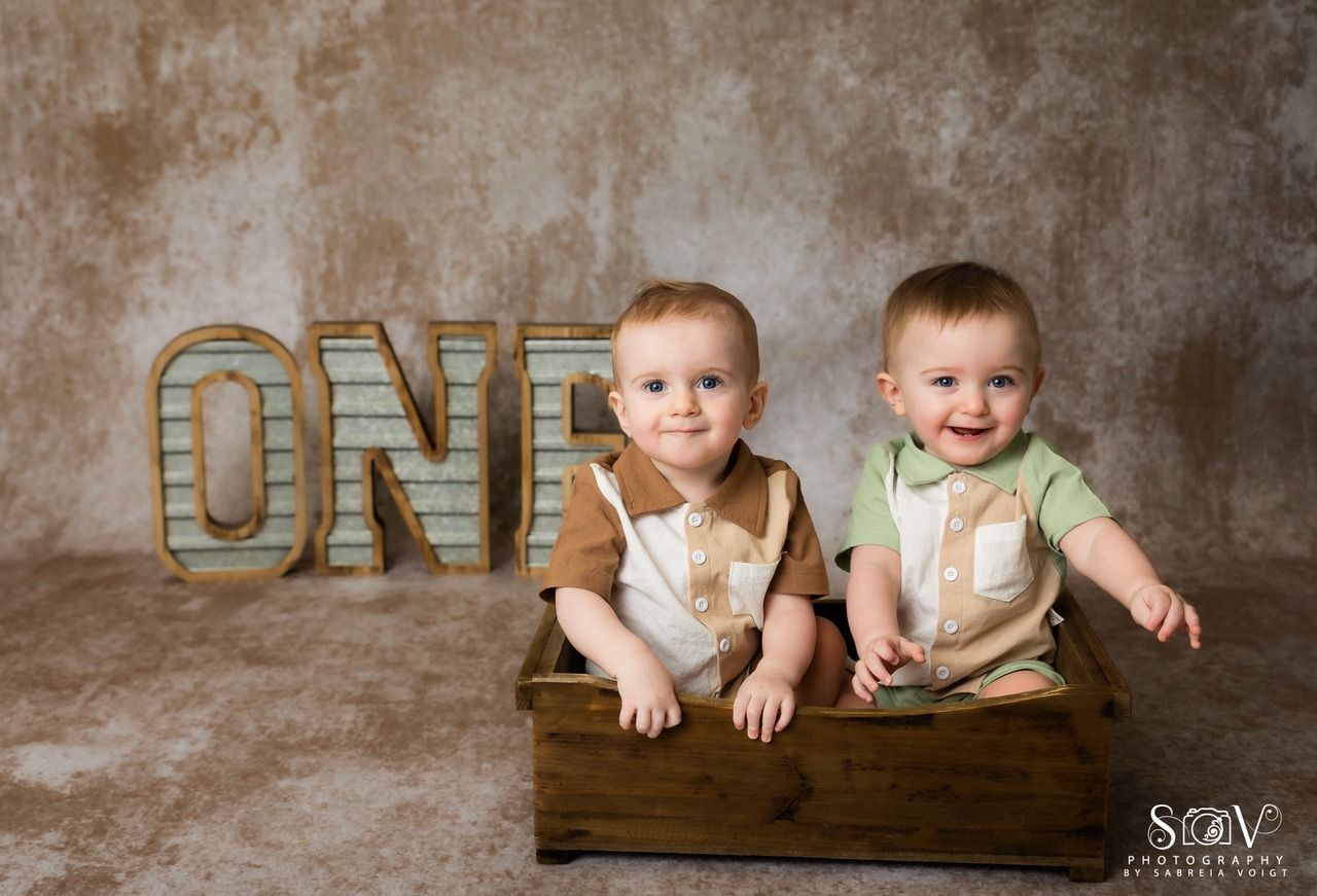 Two babies in a wooden box, smiling, with 