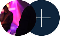Dark silhouettes in front of pink stage lights, with a navy circle and white plus sign on the right