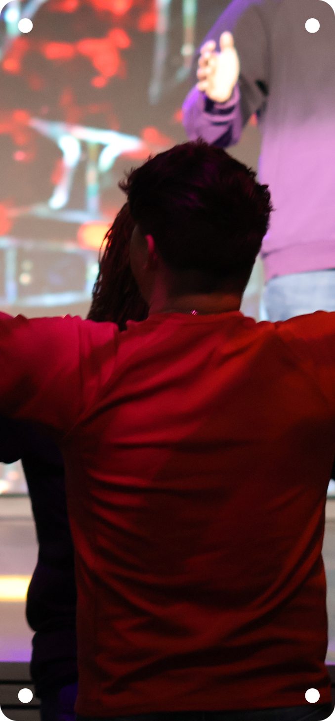 Person in a red shirt watching a stage performance with red and purple lighting