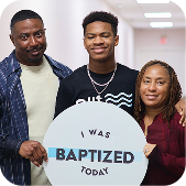 Three people smiling, holding a sign that says “I was baptized today.”