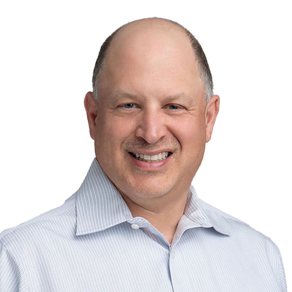 A bald man wearing a striped shirt is smiling for the camera.